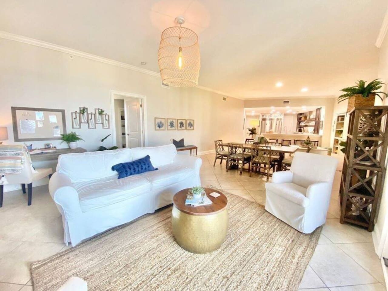 Un salon avec un canapé blanc, une table basse ronde et un coin repas comprenant une table et des chaises en bois.