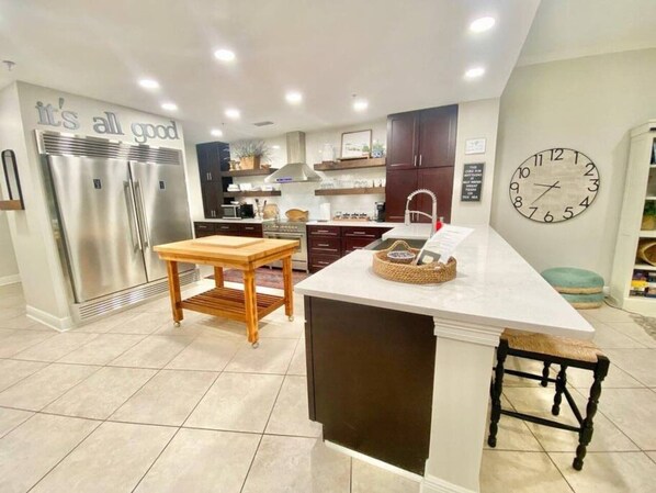A modern kitchen with stainless steel appliances, a wooden island, and a clock on the wall. - #442 Inn by the Sea 3 Bedroom Unit (Harrison County)