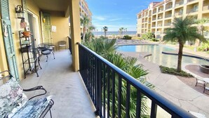 Ein Balkon mit Gartenmöbeln, einem Pool und Blick auf ein Hotelgebäude.