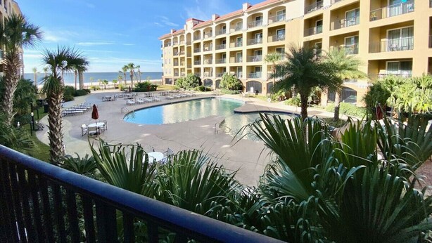 Ein Hotel mit Pool, Palmen und Meerblick.