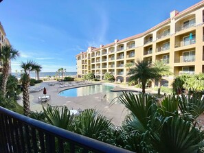 Un hotel con piscina, palmeras y vista al océano.