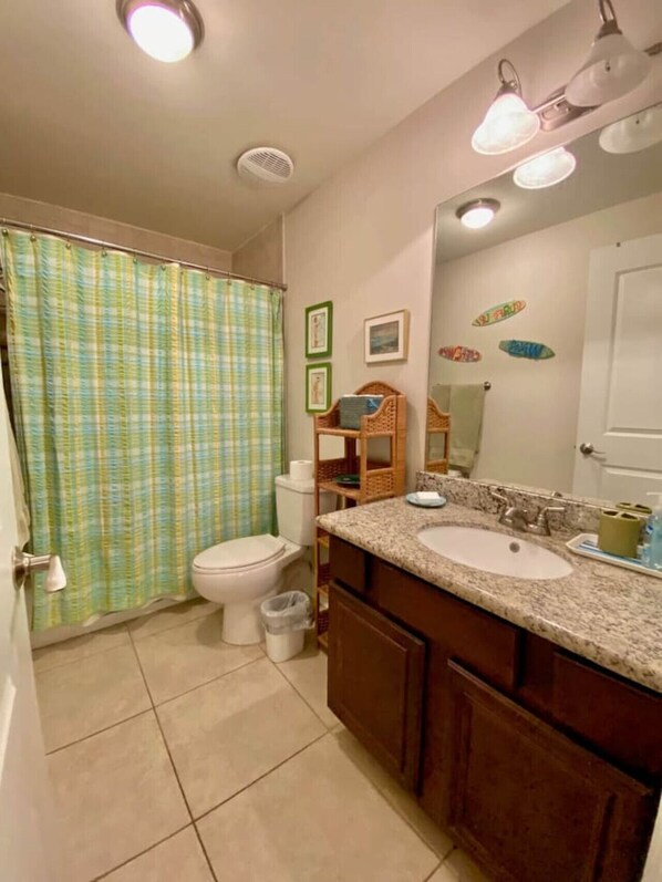 Un baño con inodoro, lavamanos y cortina de ducha.