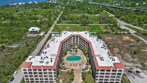 A large hotel with a central courtyard, multiple parking levels, and a view of a bridge and greenery in the background. - #631 Beautiful poolside Condo perfect for a family getaway (Harrison County)