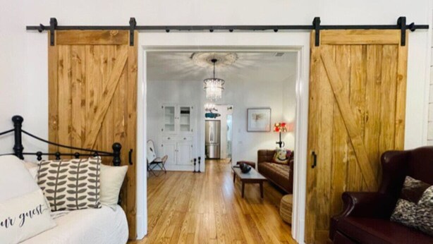 A room with a bed, a sofa, a dining table, and a chandelier.