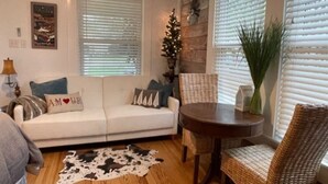 Una sala de estar acogedora con un sofá blanco, una mesa redonda y un sillón de mimbre.