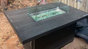 Un jacuzzi con cubierta de vidrio en un patio trasero con valla de madera y un árbol.