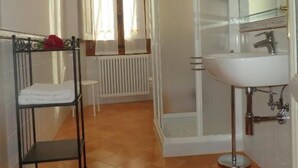 A bathroom with a white sink, a glass shower enclosure, a radiator, and a window with curtains. - Dimora Pieri - Appartamento Medici, historic building  in the old center with elevator (Firenze)