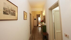A hallway with framed pictures on the walls, a wooden bench, and a door at the end. - Dimora Pieri - Appartamento Medici, historic building  in the old center with elevator (Firenze)