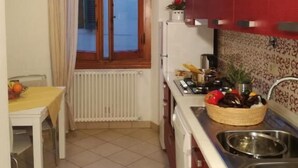 A compact kitchen with a window, a dining table, and a red cabinet. - Dimora Pieri - Appartamento Medici, historic building  in the old center with elevator (Firenze)