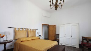 Une chambre à coucher comprenant un lit, une table de chevet, une lampe, une armoire et un lustre.