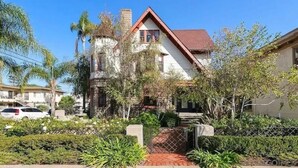 A two-story house with a red roof, surrounded by greenery and a fenced yard. - Lovely Victorian Home in the Heart of San Diego (San Diego)