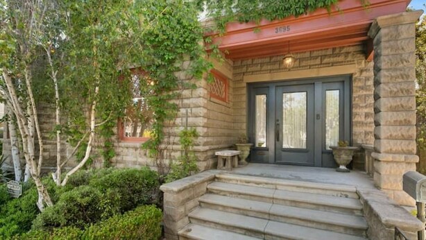 A stone building with a dark entrance door, steps leading up to it, and a small table and planter near the door. - Lovely Victorian Home in the Heart of San Diego (San Diego)