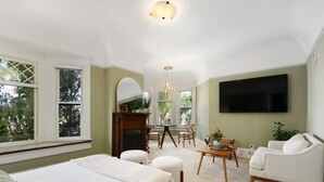 A bedroom with a large bed, a desk, a chair, and a TV mounted on the wall. - Lovely Victorian Home in the Heart of San Diego (San Diego)