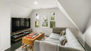 A modern living room with a flat-screen TV, a wooden coffee table, and a grey sofa. - Lovely Victorian Home in the Heart of San Diego (San Diego)