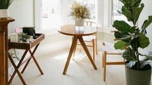 A dining area with a round table, wooden chairs, and a hanging light fixture. - Lovely Victorian Home in the Heart of San Diego (San Diego)