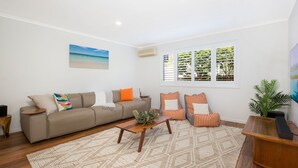 A living room with a beige sofa, striped armchairs, a wooden coffee table, and a large window with blinds. - Banksia by the Bay, Jervis Bay (Vincentia)