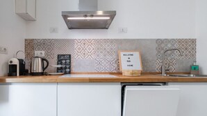 A modern kitchen with a coffee machine, kettle, and a welcome sign.