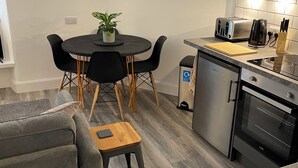 A modern kitchen with a dining area, including a table with chairs, a small potted plant, and a toaster. - No.4 May Terrace (Inverness)