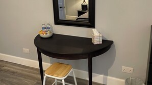 A small, dark wooden console table with a white stool, a mirror, a tissue box, and a bowl of ice cream on it. - No.4 May Terrace (Inverness)