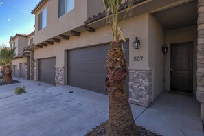 A residential building with a stone facade, numbered 507, featuring a garage and a well-maintained palm tree in the driveway. - Top Tier Townhome in Washington Utah Private Spa, Pool, Firepit. VS507 (Washington)