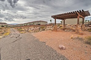 A desert landscape with a paved road, a wooden pergola, and a row of houses in the background. - Top Tier Townhome in Washington Utah Private Spa, Pool, Firepit. VS507 (Washington)