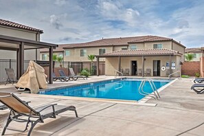 A swimming pool with lounge chairs and a covered seating area, surrounded by buildings with a tiled roof. - Top Tier Townhome in Washington Utah Private Spa, Pool, Firepit. VS507 (Washington)