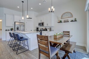A modern kitchen with white cabinets, stainless steel appliances, and a bar area with blue bar stools. - Top Tier Townhome in Washington Utah Private Spa, Pool, Firepit. VS507 (Washington)