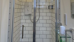 A glass-enclosed shower with a control panel, white tiled walls, and a hanging light fixture. - City Apartment - No.1 May Court (Inverness)