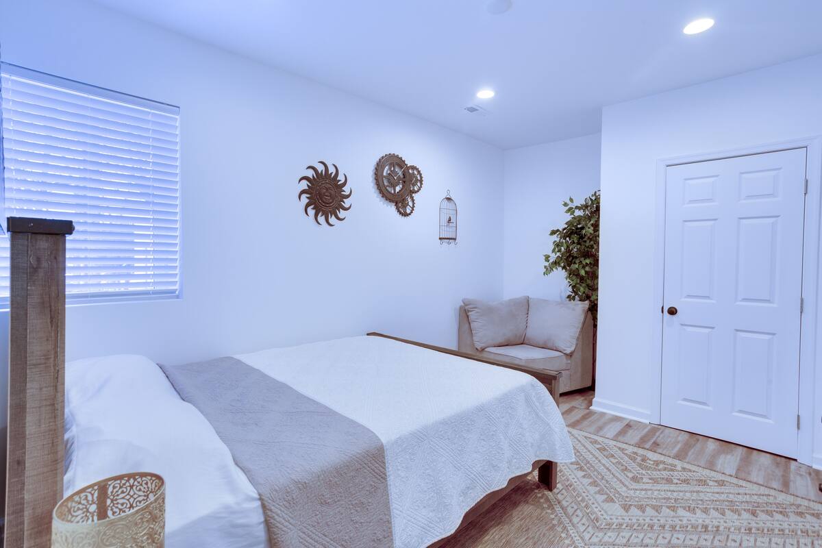 A bedroom with a bed, a chair, a door, and wall decorations.