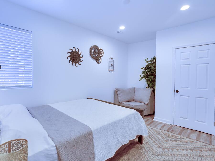 Un dormitorio con cama, una silla, una puerta y adornos en la pared.