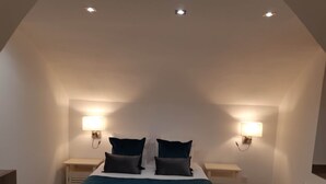 Un dormitorio con una cama grande, dos mesitas de noche y dos lámparas de pared.