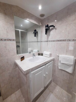 Un baño moderno con un espejo grande, un lavamanos y un secador de pelo fijado a la pared.