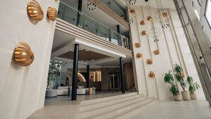 A modern hotel lobby with a spacious seating area, a staircase leading to the upper floor, and decorative wall sconces. - TUI SUNEO PERLA ADULTS ONLY (Sunny Beach)