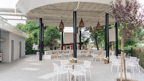 An outdoor seating area with white chairs and tables, surrounded by black columns and hanging wicker lamps. - TUI SUNEO PERLA ADULTS ONLY (Sunny Beach)