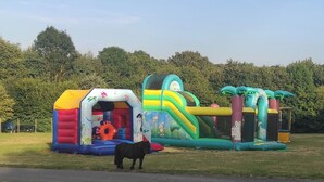 A colorful inflatable play structure with slides and tunnels, set in a grassy area with trees in the background. - Gîte au Bord de l' eau Proche du Puy du Fou et du Parc Oriental de Maulévrier ! (Maulevrier)