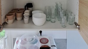 A kitchen with white shelves holding various glassware and dishes.
