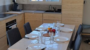 A modern kitchen with wooden cabinets, a dining table set for four, and a window providing natural light.