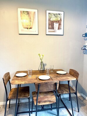 Un tavolo da pranzo con quattro sedie, un vaso con fiori e due quadri appesi al muro.