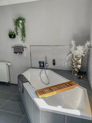 Un bagno moderno con una vasca freestanding, un portasciugamani, un termosifone e piante decorative.