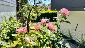 Ein Garten mit rosa Rosen und einem kleinen Baum.