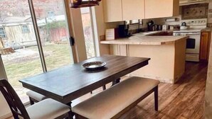 A modern kitchen with a dining area, wooden flooring, and a built-in island. - Enjoy a Sweet Retreat in Kanab, Utah. Walking distance to all downtown Kanab has to offer. Close to Zion, Bryce Canyon, and the Grand Canyon! (Kanab)