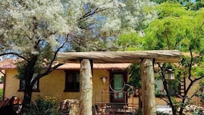 A rustic outdoor area with a wooden pergola, a stone pathway, and a building with a yellow facade. - Enjoy a Sweet Retreat in Kanab, Utah. Walking distance to all downtown Kanab has to offer. Close to Zion, Bryce Canyon, and the Grand Canyon! (Kanab)
