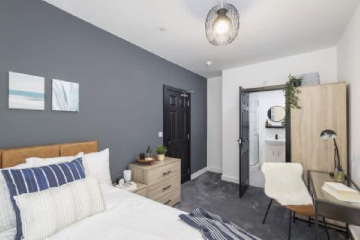 A modern bedroom with a bed, a dresser, a chair, and a desk.