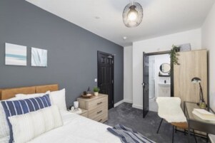 Un dormitorio moderno con cama, cómoda, silla y escritorio.