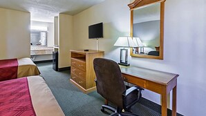 Ein Hotelzimmer mit zwei Betten, einem Schreibtisch mit Stuhl, einem Fernseher, einem Spiegel und einer Kommode.