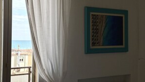 A room with a view of the sea through a window, a framed picture on the wall, and a curtain partially drawn. - SE041 - Senigallia,  four-room apartment super equipped 150m from the sea (Senigallia)