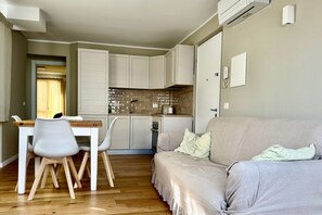 Un espace de vie compact comprenant un coin cuisine, un coin repas avec des chaises et un canapé.
