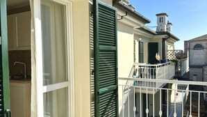 A residential building with a balcony, a window with shutters, and a visible kitchen area. - P016 - Porto Recanati, new three-room penthouse 30m from the sea (Porto Recanati)