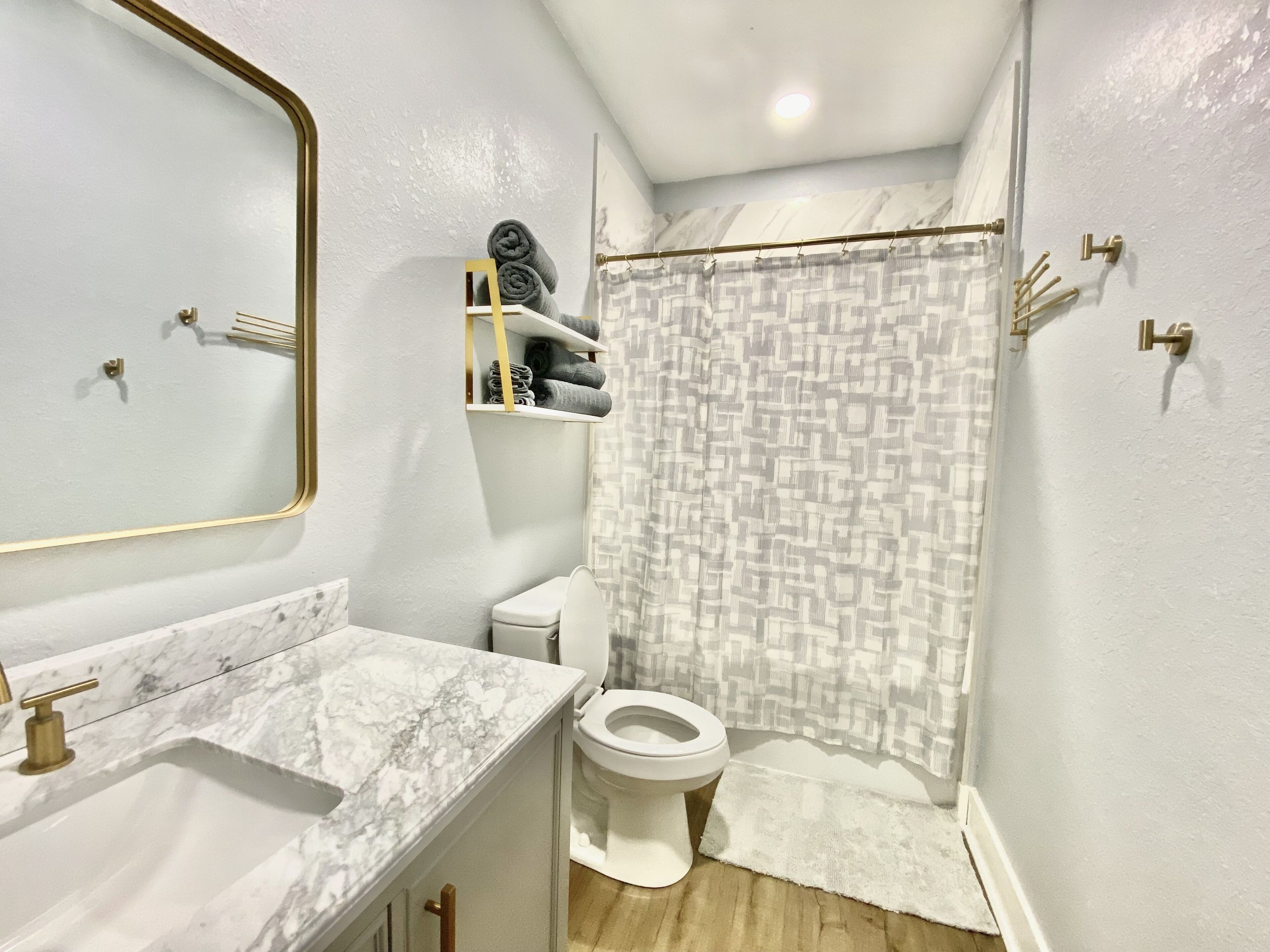 Ein Badezimmer mit Marmorwaschbecken, Toilette, Duschvorhang und Handtuchhalter.