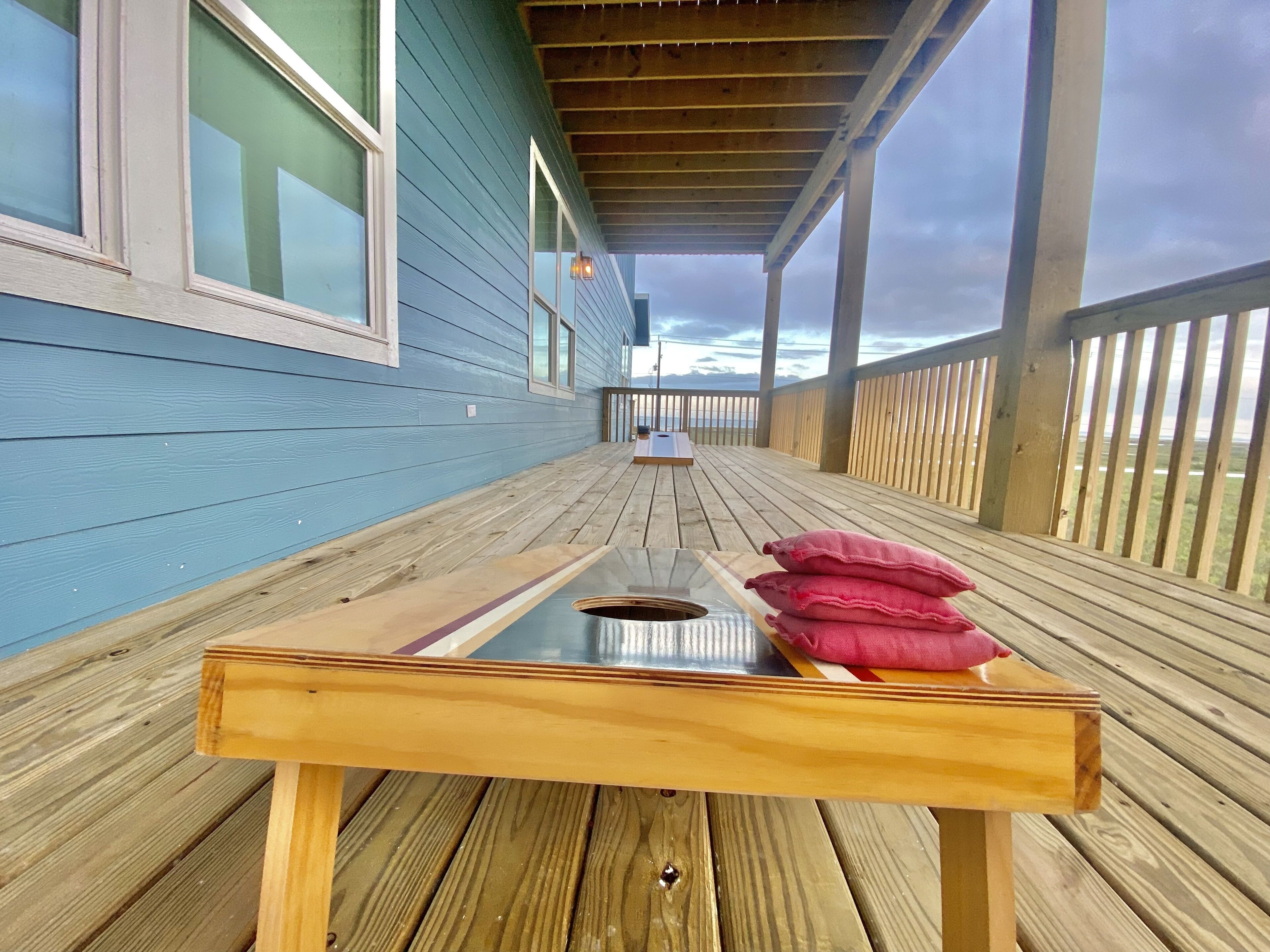 Terraza de madera con una mesa y cojines, con vistas a un cuerpo de agua.